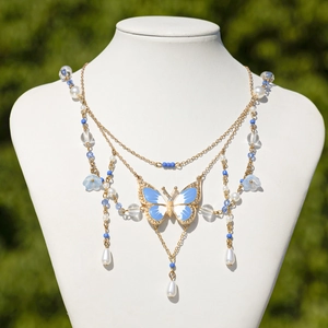 Detail einer mehrlagigen Schmetterlings-Choker-Kette mit Perlen und blauen Emaille-Anhänger