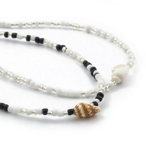 Detail van bohemien tailleketting met witte kralen en natuurlijke schelphangers