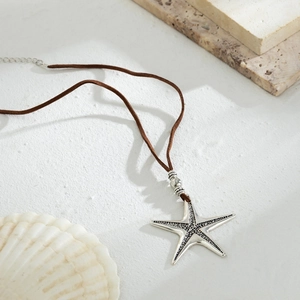 Macro detail of silver starfish pendant with textured finish on brown velvet cord necklace