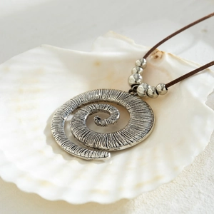 Macro detail of bohemian spiral conch pendant with vintage silver finish and metal beads