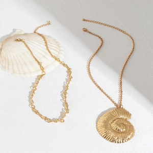 Macro shot of gold nautilus shell pendant and starfish necklace with metal shell chain