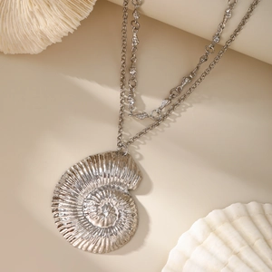 Detailed close-up of a nautilus shell pendant on a double-layer silver chain necklace