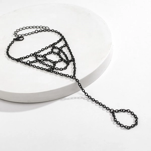 Dettaglio del bracciale ad anello regolabile in metallo nero con design a ragnatela e catenella