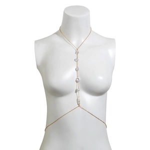 Golden body chain with baroque pearls on a white mannequin for beach vacation style