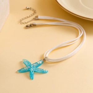 Macro shot of blue resin starfish pendant with glitter on a white cord necklace