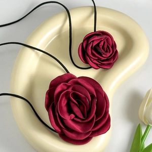 Detail of burgundy satin rose chokers in two sizes on a ceramic tray with tulip