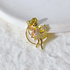 Close-up of gold-plated fairy pendant on crescent moon with pink zircon wings