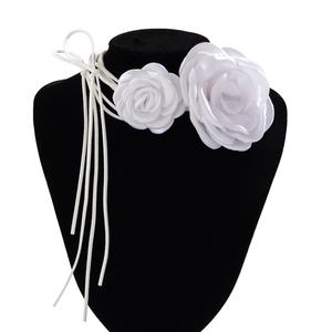 Close-up of white fabric rose choker with long ribbons on a black jewelry stand