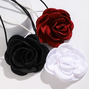 Detailed view of satin rose chokers in red, black, and white colors on a clean pedestal