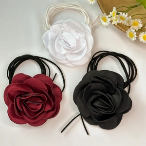 Close-up of 3D satin rose choker necklaces in cream, burgundy, and black fabric