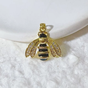 Detailed macro view of a gold-plated bee pendant with micro-paved zircons and black enamel