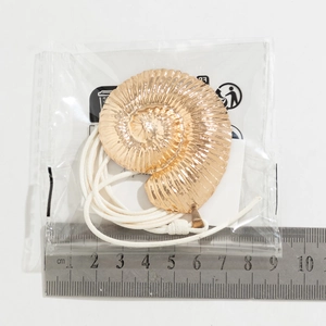 Detail view of a large golden conch shell pendant with rope chain on a scale