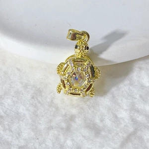 Golden turtle pendant with white zircons and hexagonal faceted crystal on fur background