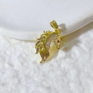 Golden unicorn pendant with micro-set zircons and a red stone eye on white plush background