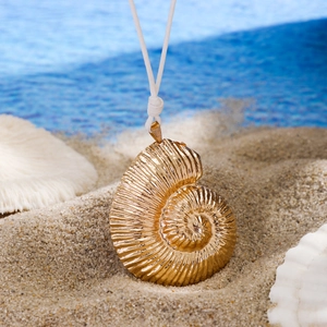 Detailed close-up of golden conch shell pendant with spiral texture on sandy beach