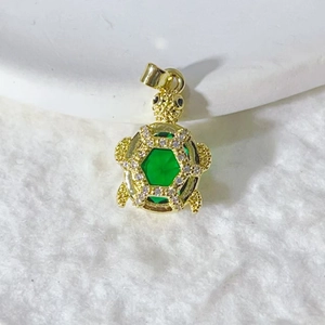 Detailed close-up of golden sea turtle pendant with green crystal and pavé zircons