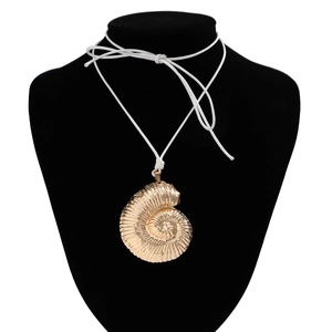 Detailed view of the gold seashell nautilus pendant with white waxed cord on black bust