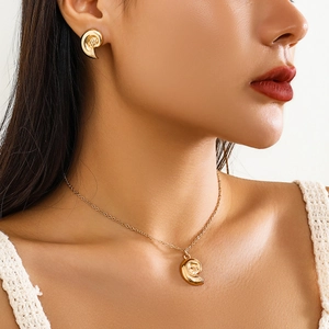 Close-up of a gold spiral necklace and earring set with star patterns and small diamonds