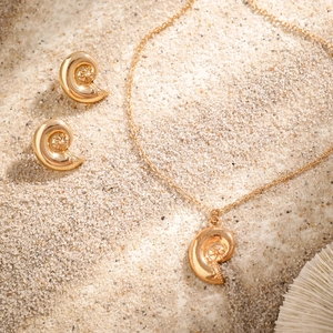 Golden starfish and conch jewelry set with necklace and earrings on beach sand