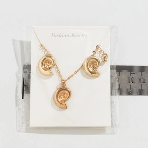 Detailed view of bohemian conch shell pendants on gold chain with measurement ruler