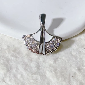 Macro shot of silver ginkgo leaf pendant with white enamel and sparkling zircons