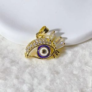 Détail macro du pendentif œil porte-bonheur plaqué or 18k avec émail bleu et oxydes de zirconium