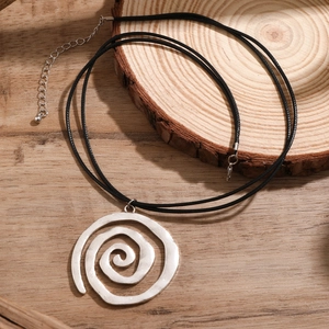 Detailed macro of spiral shell pendant on black cord with hammered silver texture