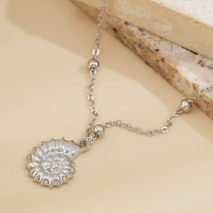 Macro shot of silver seashell pendant with detailed spiral texture and soft studio lighting