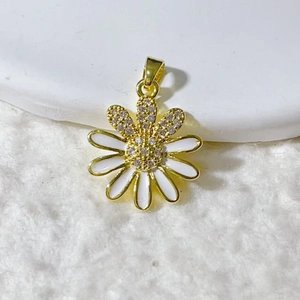 Macro shot of gold-plated daisy pendant with white enamel petals and sparkling zircons