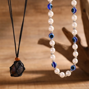 Detail der Evil Eye Perlenkette und Kordelhalskette mit Naturstein auf Holzständer