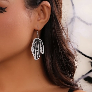 Detail of Halloween skeleton hand acrylic earrings worn with thematic spider web backdrop