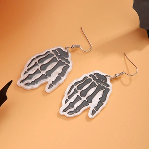 Detail of Halloween skeleton hand earrings with pearl finish on orange background