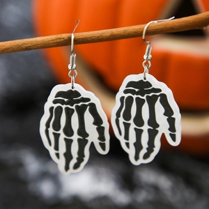 Macro detail of Halloween acrylic skull hand earrings hanging on a natural wooden branch