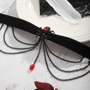 Nahaufnahme eines Gothic-Samtchokers mit roter Edelstein-Spinne und hängenden Metallketten