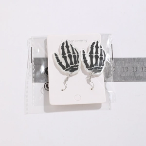 Detail view of gothic skeleton hand acrylic earrings with ruler for size reference