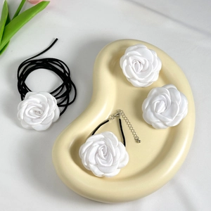 Λεπτομέρεια από λευκά σατέν τριαντάφυλλα chokers και αξεσουάρ μαλλιών σε κεραμικό δίσκο