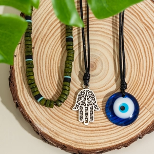 Details von Hamsa-Hand und blauem Evil Eye-Schmuck auf natürlichem Holzhintergrund