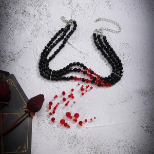 Detailed view of Gothic choker with red crystal blood drops and black beads on stone surface