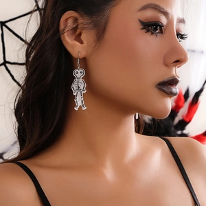 Close-up of Halloween skull drop earrings worn by a model in a dark gothic setting