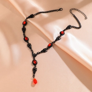 Detail of Gothic bat pendant necklace featuring red ruby stones on silk fabric