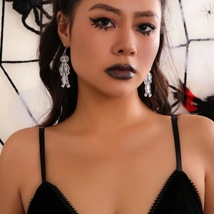 Close-up of gothic skeleton earrings worn by model with dark makeup and spider web backdrop