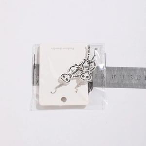 Close-up of skeleton acrylic drop earrings on a white jewelry card for Halloween