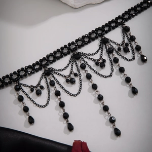 Detail of gothic black beaded choker featuring layered metal tassels and teardrop pendants