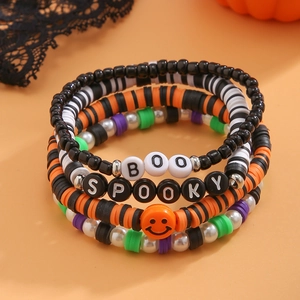 Dettaglio di bracciali elastici di Halloween con perline BOO e SPOOKY su sfondo arancio