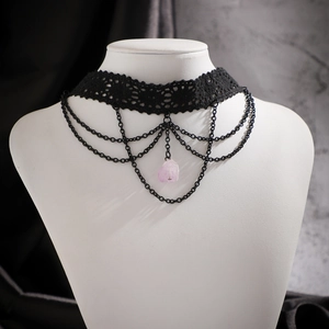 Gros plan d'un choker en dentelle noire avec chaînes et pendentif en cristal violet