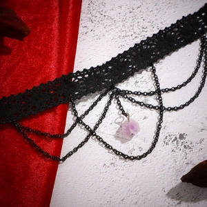 Détail du choker gothique en dentelle noire avec pendentif en pierre violette et chaînes