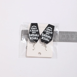 Close-up of Halloween acrylic coffin earrings with text and measurement ruler