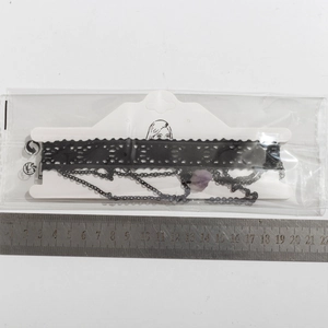 Détail du ras de cou en dentelle noire avec cristal violet et chaînes métalliques
