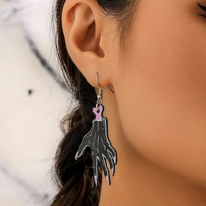 Close-up of Halloween acrylic severed hand earrings with pink nails and bone detail