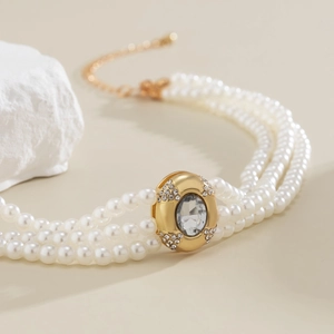 Gros plan détaillé d'un collier à trois rangs de perles avec un pendentif en cristal